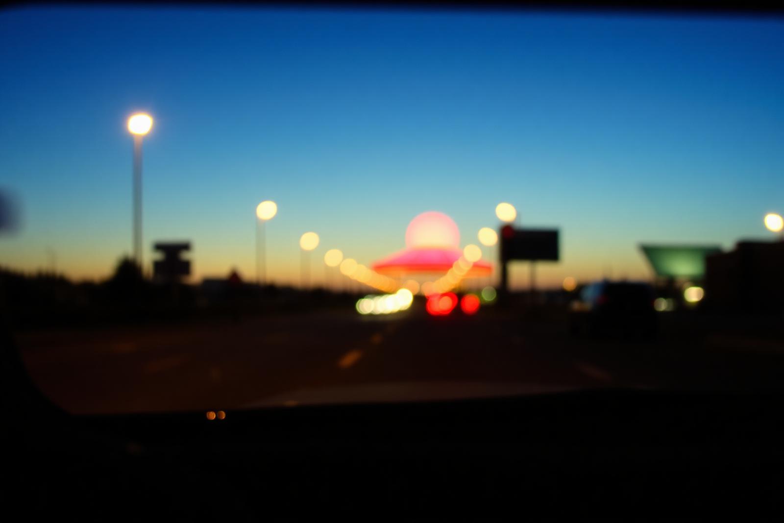 Warm streetlights blurred through a windshield at dusk